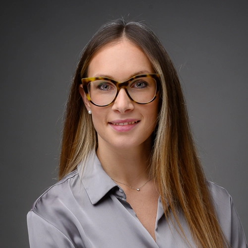 ritratto in studio, ragazza di tre quarti con camicia grigia su fondo scuro. Fotografo specializzato in ritratti professionali a Pordenone. Realizzo servizi fotografici per privati e aziende